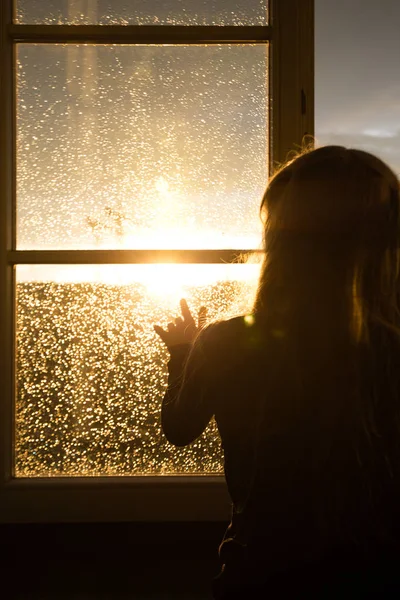Meisje zittend op een vensterbank en kijken naar de avond stad — Stockfoto