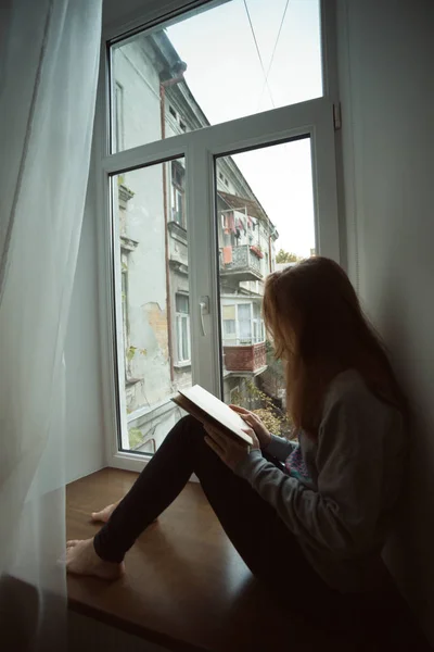 Adolescente chica sentado en un alféizar de la ventana — Foto de Stock