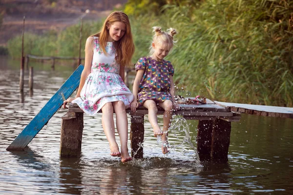 Mother and daughter sitting on the pier — Stock Photo, Image