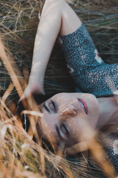 Lány fekszik, száraz fű — Stock Fotó