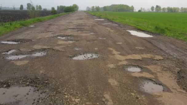 雨の後にピットホールや水たまりがたくさんある悪い田舎道 — ストック動画