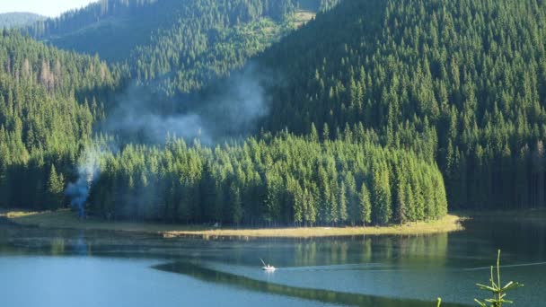 朝日に照らされた松の丘を持つ朝の山湖の漁師ボート — ストック動画