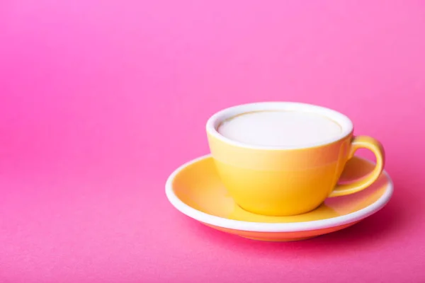 Gelbe Tasse auf rosa Hintergrund — Stockfoto