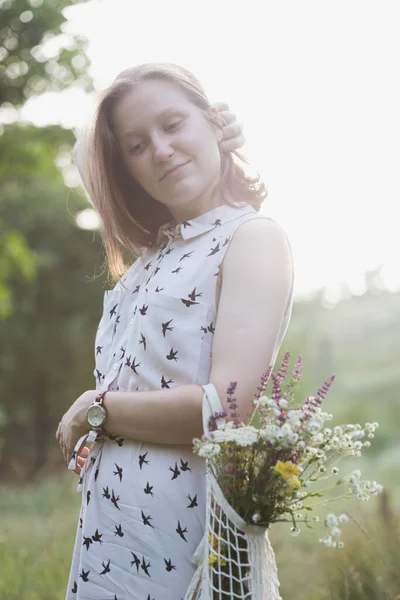 一个带着花束的夏天姑娘穿过草地 夏天的心情和灵感 — 图库照片