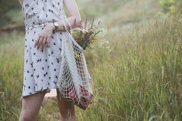 花束を持つ少女が牧草地を歩く 夏の気分とインスピレーションは — ストック写真