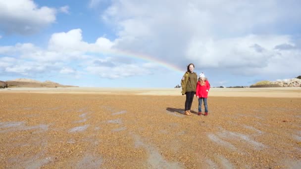 干潮時の砂の上に立つ曇り空の虹を見ている子供たち ブルターニュ フランス — ストック動画