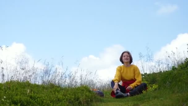 Genç Bir Yürüyüşçü Çimenli Bir Tepede Oturuyor Dinleniyor Arkaplanda Bulutlar — Stok video