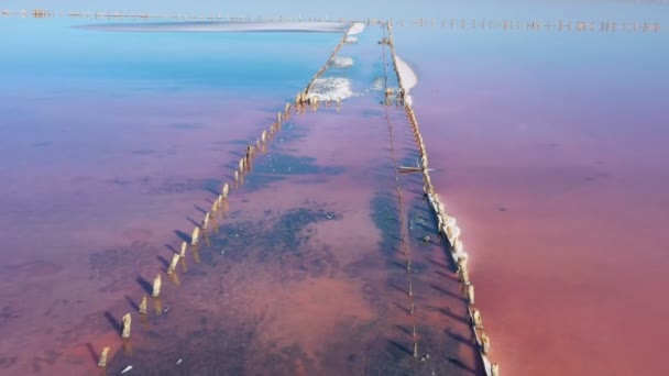 Terk Edilmiş Tuz Çıkarma Fabrikasının Ahşap Sütunlarıyla Pembe Tuz Gölü — Stok video