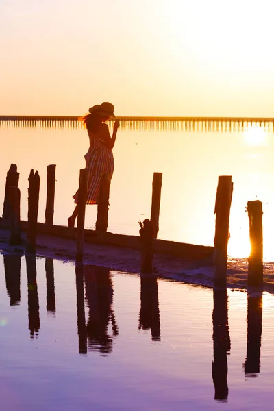 有名なピンク色の塩湖で日没時にポーズをとる少女 暗闇の中での反射 — ストック写真
