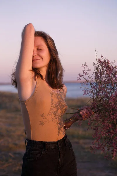 海を背景に花の花束を持つ少女 休暇やインスピレーションは — ストック写真