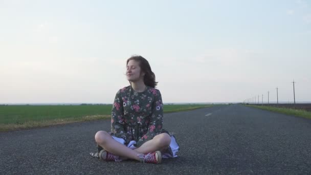 Mladá Usměvavá Dívka Sedí Prázdné Venkovské Silnici Větrného Oblačného Dne — Stock video