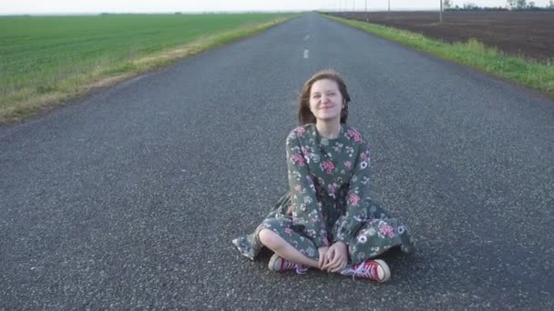 Young Smiling Girl Sitting Empty Rural Road Windy Cloudy Day — Stock Video