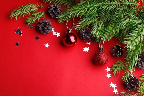 一个圣诞节的背景 圣诞树小树枝 圣诞球和红色背景的球果 — 图库照片
