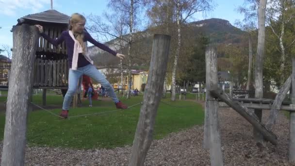 晴れた日に小さなヨーロッパの村の木の遊び場で遊んでいる子供の女の子 — ストック動画