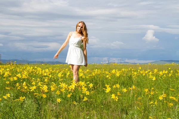 Dziewczyna Białej Sukni Jest Chodzenie Wśród Kwiaty — Zdjęcie stockowe