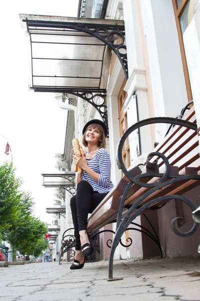 Genç kız bir bankta oturur ve bir rulo tutar