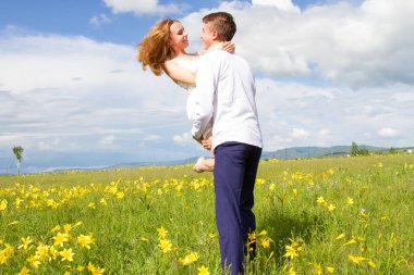 Genç çift çiçekler arasında bir alanda yürüyüş