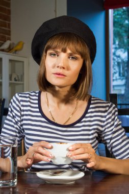 kız bir bere içinde bir kafede bir masada oturuyor