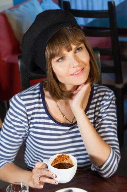 Genç kız bir kafede bir masada oturuyor