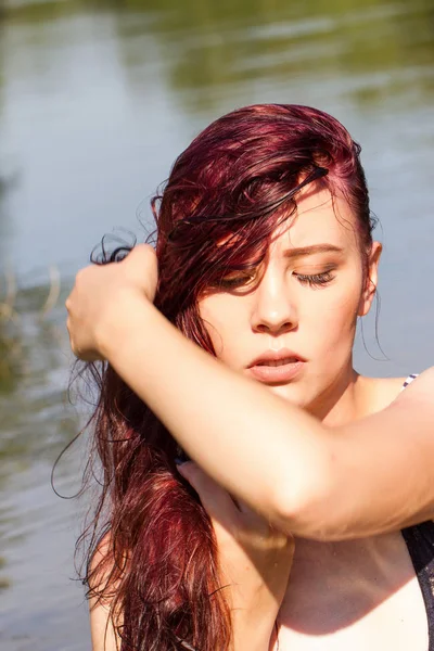 Kızıl saçlı kız ıslak T-shirt bir su birikintisi arka planı çizgili.