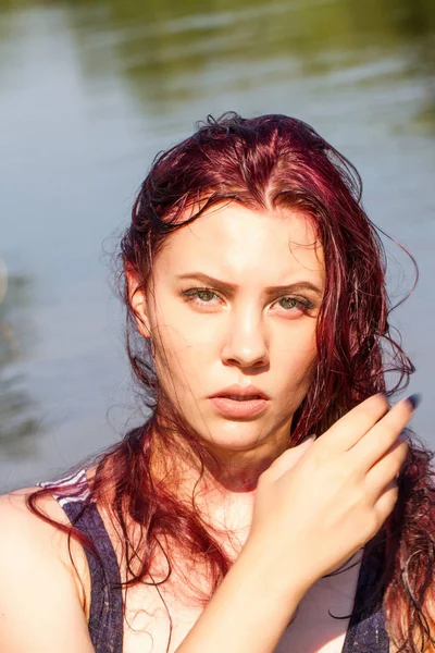 红头发的女孩在湿条纹 T恤衫对池塘的背景 — 图库照片