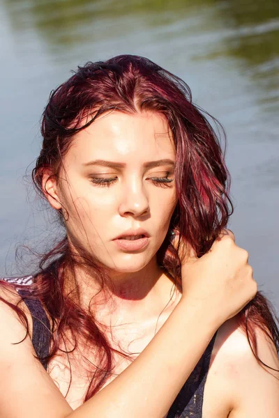 Kızıl saçlı kız ıslak T-shirt bir su birikintisi arka planı çizgili.