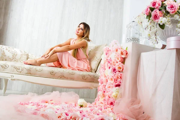 Genç kız çiçeklerle dekore edilmiş bir odada oturur