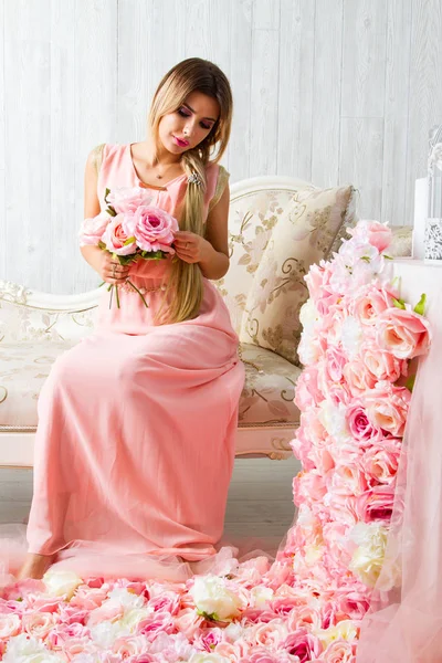 Genç kız çiçeklerle dekore edilmiş bir odada oturur