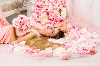 Genç kız çiçeklerle dekore edilmiş bir odada oturur