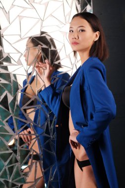 Asyalı kız mavi ceket ve kırık bir ayna arka plan üzerinde siyah iç çamaşırı