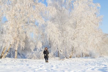 kadın karla kaplı ağaçlar arasında Ormanda yürür