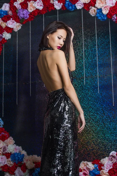 バラのアーチの背景にイブニング ドレスの少女 — ストック写真