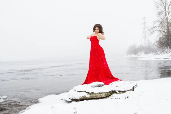 積雪の中 川のほとりに赤いイブニング ドレスの少女 — ストック写真