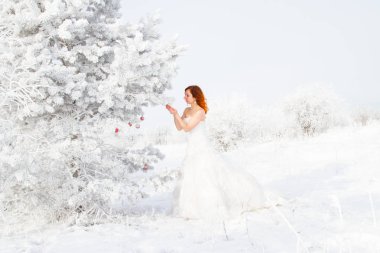 Gelin bir buz kaplı Noel ağacının yanında duruyor. Kış portresi