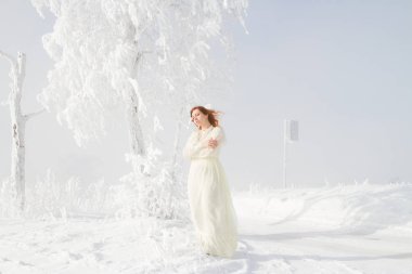 Karla kaplı ağaçlar arka plan üzerinde kırmızı saçlı Genç kız. Kış portresi