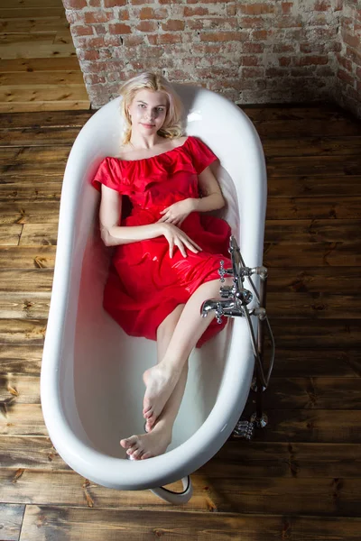 Blonde in a wet dress sitting in a bathroom with water