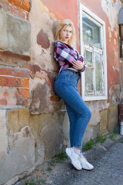 Harap bir evin duvarında duran sarışın