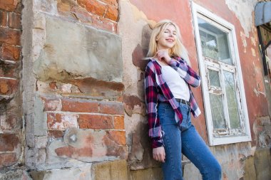 Harap bir evin duvarında duran sarışın