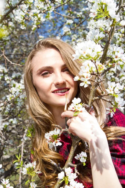 リンゴの木の開花枝の間に明るいメイクを持つ女の子 — ストック写真