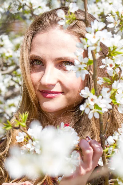 リンゴの木の開花枝の間に明るいメイクを持つ女の子 — ストック写真