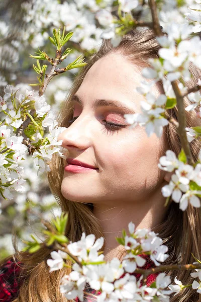 リンゴの木の開花枝の間に明るいメイクを持つ女の子 — ストック写真