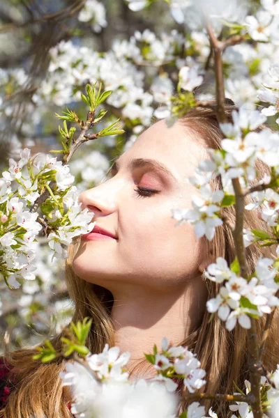 リンゴの木の開花枝の間に明るいメイクを持つ女の子 — ストック写真