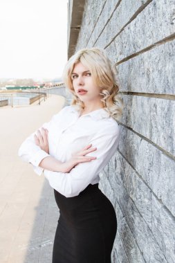 Granit duvarın yanında beyaz gömlekli genç bir sarışın.