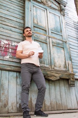 eski bir ahşap evin arka planına karşı bir kağıt uçak ile adam