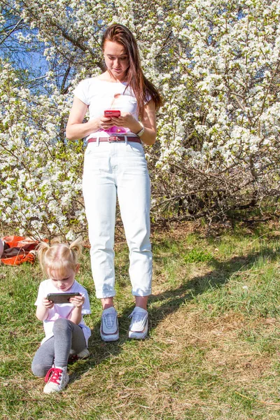 Mom and daughter are looking at the screen of the smartphone. Gadget addiction