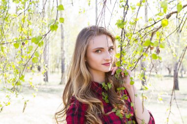 Genç kız bahar parkında yürüyor.