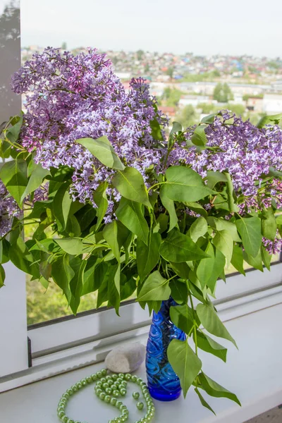 large bouquet of lilacs in a vase on the windowsill