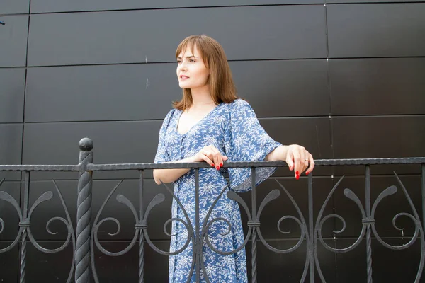 金属のフェンスの近くに立っているロマンチックな若い女の子 暗い背景 — ストック写真