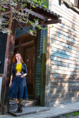 Eski ahşap evin yakınında kızıl saçlı genç kız