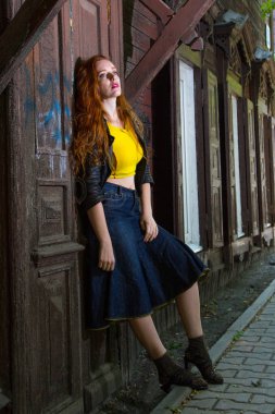 Kızıl saçlı kız eski ahşap evde duruyor